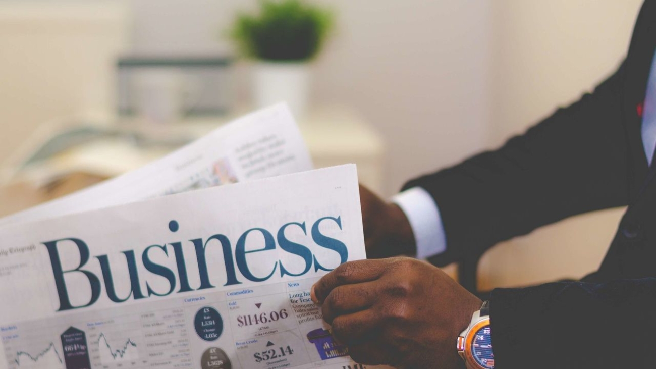 Close-up of a businessman reading a newspaper indoors, focusing on business headlines.