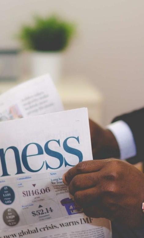 Close-up of a businessman reading a newspaper indoors, focusing on business headlines.